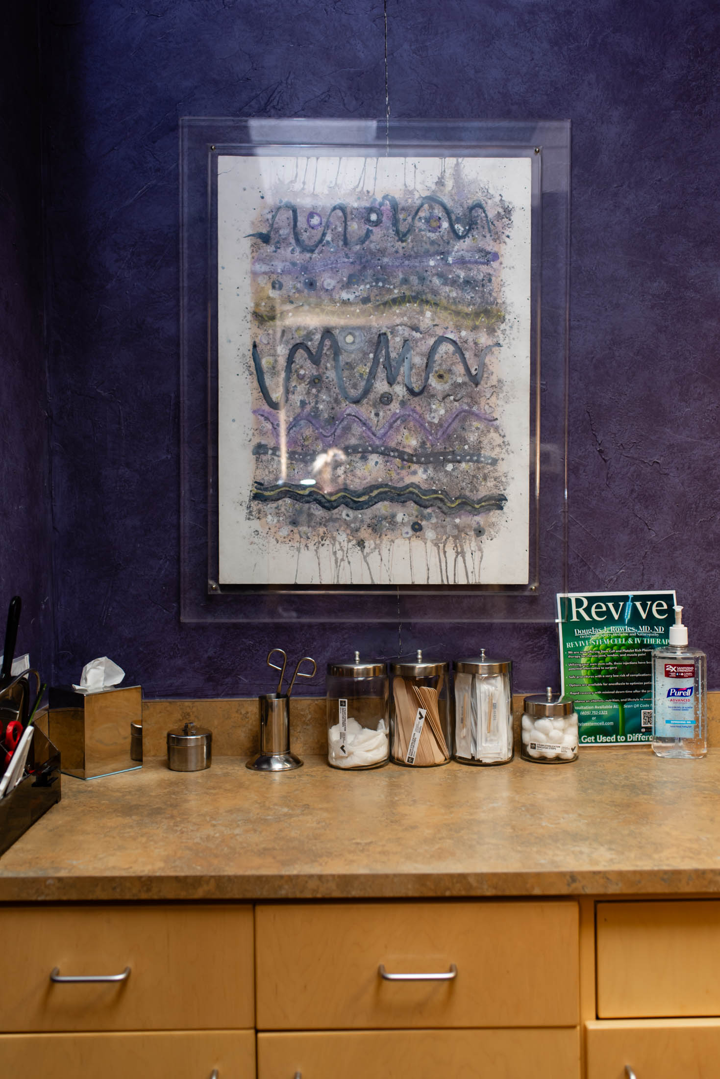 Art above countertop with jars and magazine.